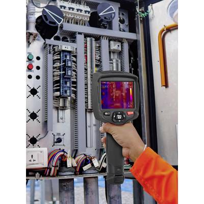 Eine Person hält eine Wärmebildkamera vor einem elektrischen Schaltschrank. Der Bildschirm zeigt Temperaturunterschiede.