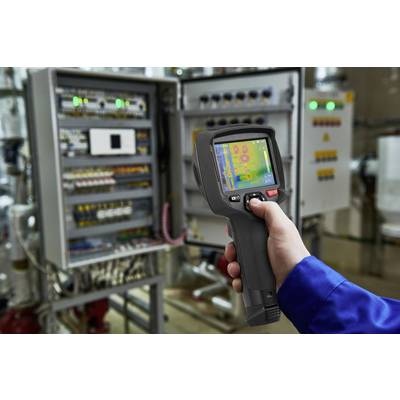 Eine Person misst mit einem Handscanner die Temperatur elektrischer Schaltschränke in einer industriellen Umgebung.