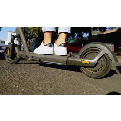 Ein Elektroroller auf einer Straße mit einer Person, die weiße Sportschuhe trägt, zeigt aktive Fortbewegung in urbaner Umgebung.