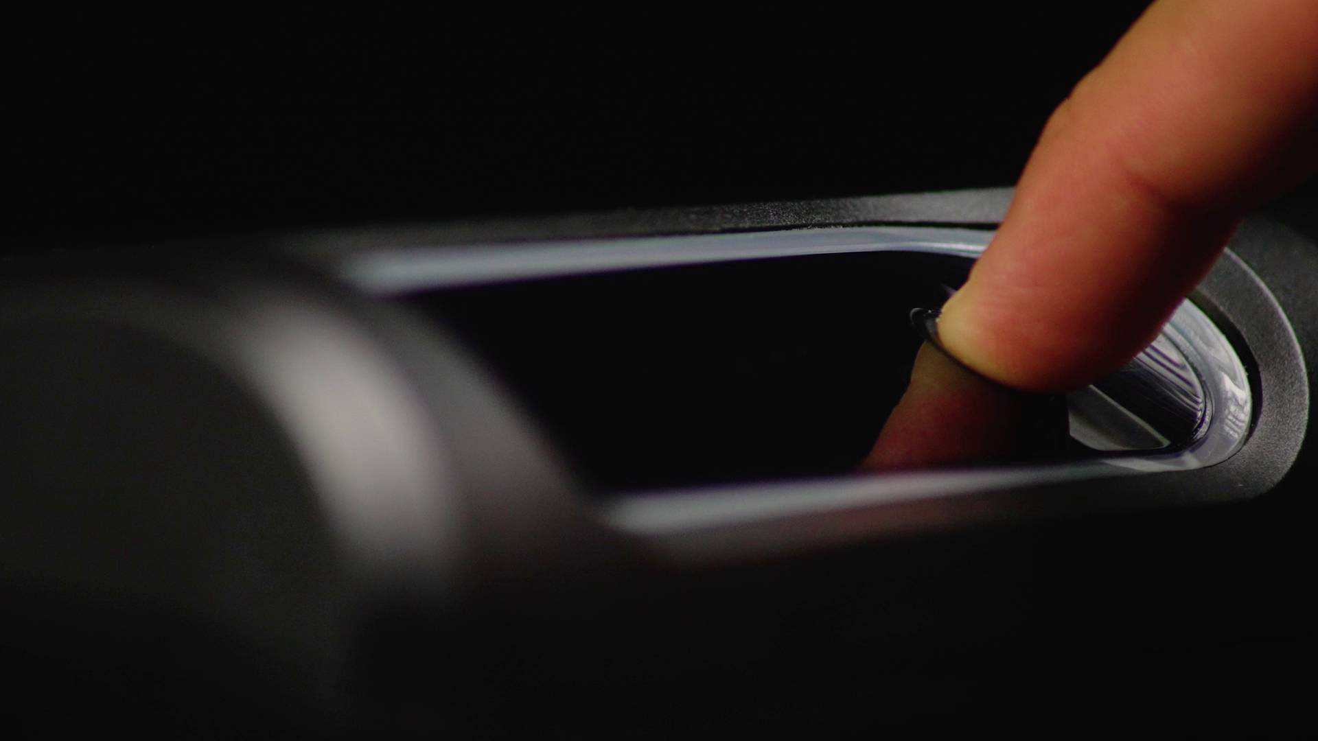 Ein Finger berührt einen Fingerabdruckscanner auf einem dunklen Hintergrund, möglicherweise zur Identifizierung oder Zugriffskontrolle.