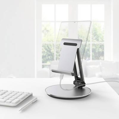 Tablet auf einem Ständer neben einer Tastatur auf einem Schreibtisch, mit einem Fenster im Hintergrund.