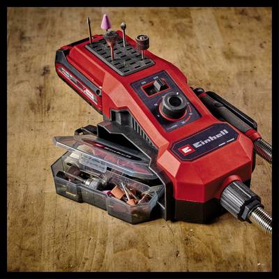 Ein rotes, tragbares Multitool mit verschiedenen Bohr- und Schleifaufsätzen auf einem Holztisch. Zubehör ist in einer transparenten Box.