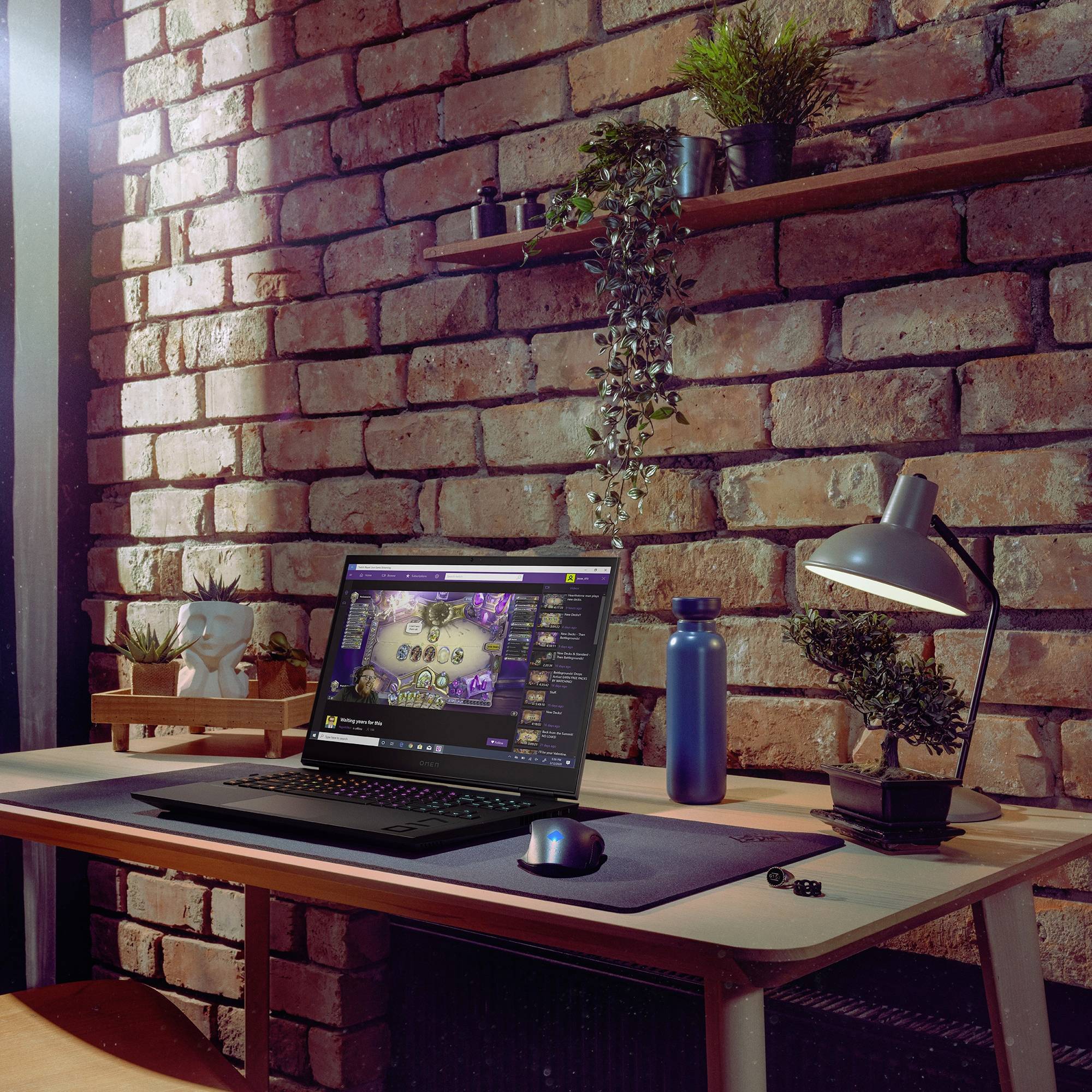 Ein gemütlicher Arbeitsplatz mit einem Laptop auf einem Holztisch vor einer Ziegelwand. Pflanzen und Lampe sorgen für eine einladende Atmosphäre.