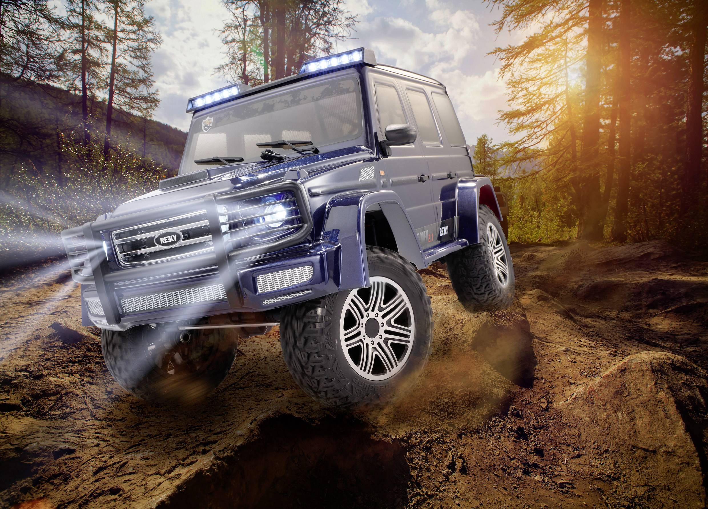 Ein blauer Geländewagen fährt durch unwegsames, schlammiges Gelände in einem Wald bei Sonnenuntergang. Die Scheinwerfer sind eingeschaltet.