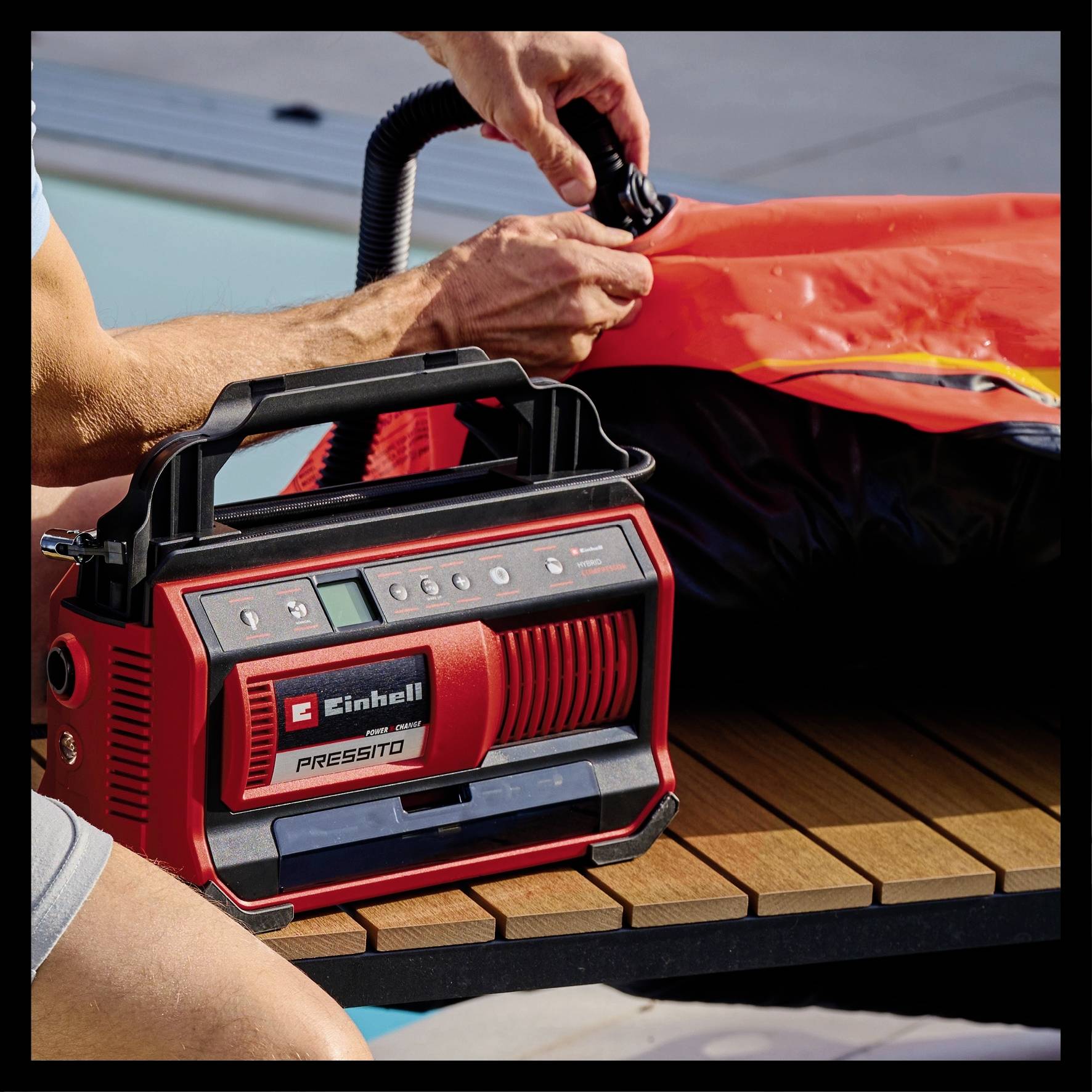 Eine Person verwendet eine rote elektrische Pumpe, um ein aufblasbares Objekt auf einem Holztisch aufzupumpen.