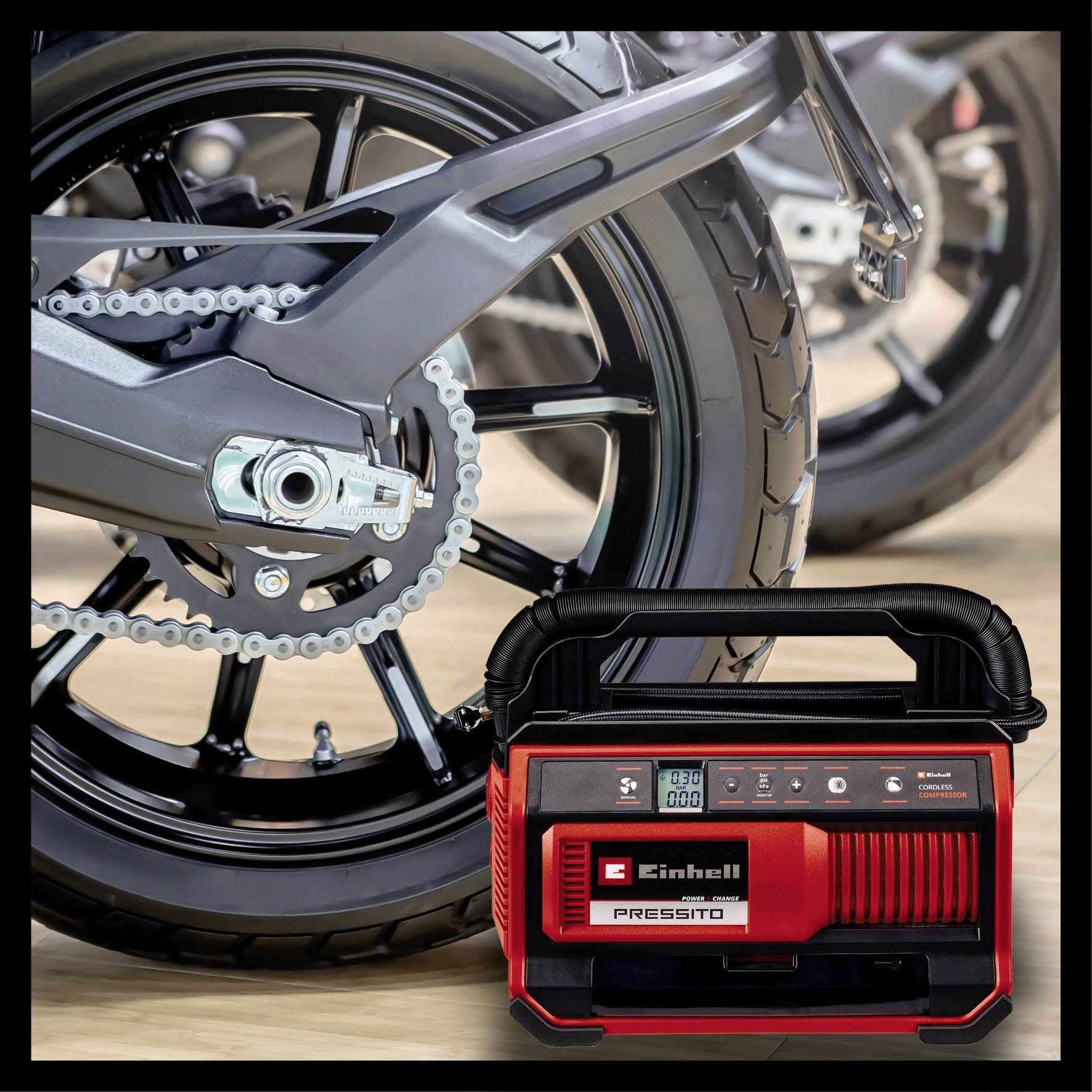 Ein roter, tragbarer Kompressor der Marke Einhell vor zwei Motorradreifen. Der Kompressor zeigt einen digitalen Bildschirm auf der Vorderseite.