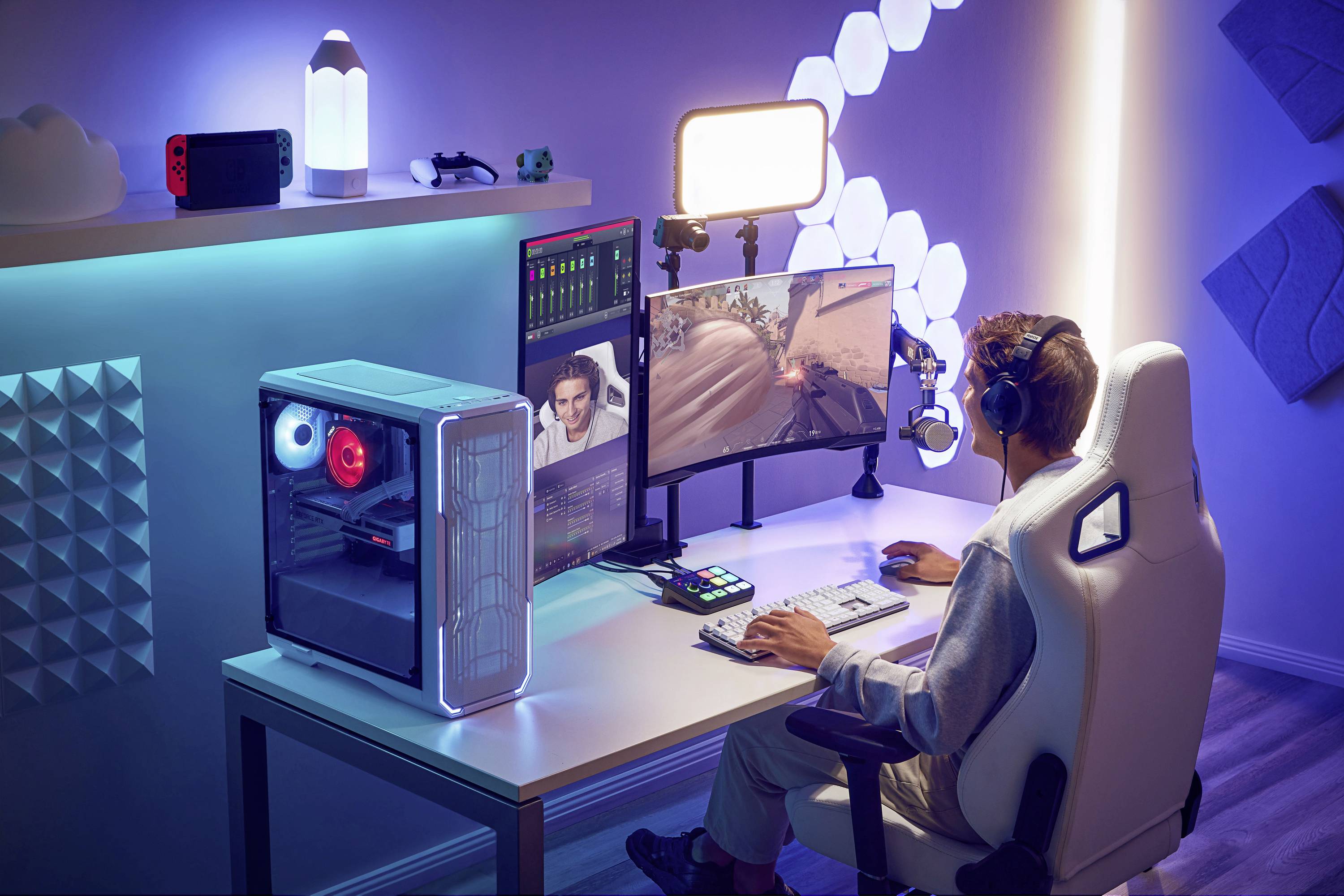 'Person spielt Videospiel auf Computer mit zwei Bildschirmen, umgeben von LED-Leuchten und Gaming-Setup; Fokus auf Actionspiel.'