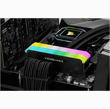 'Nahaufnahme eines Computermotherboards mit mehrfarbig beleuchtetem RAM-Modul namens Vengeance, montiert über der CPU mit Kühler.'