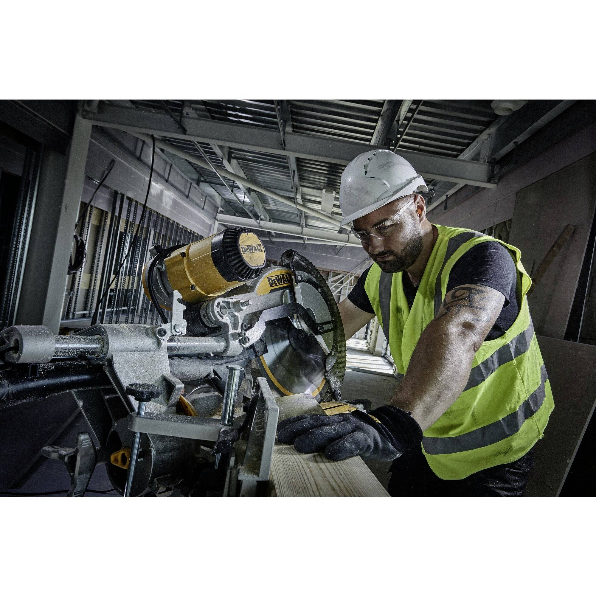 Ein Bauarbeiter mit Sicherheitsweste und Helm schneidet Holz mit einer Kreissäge in einem industriellen Innenraum.