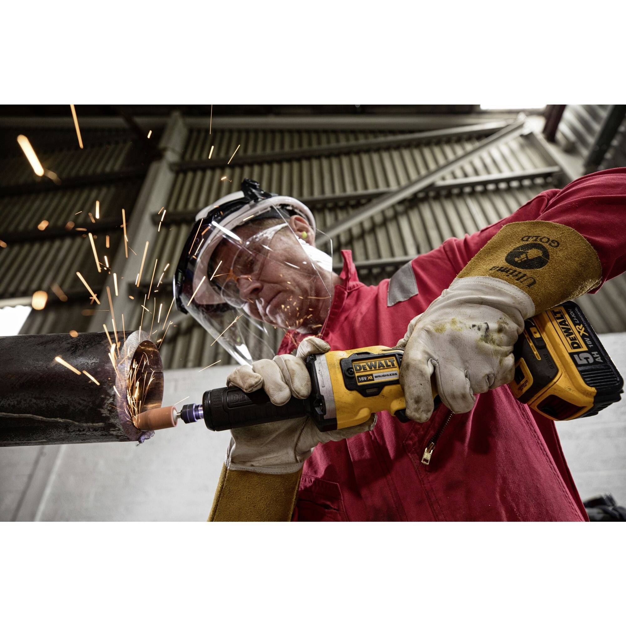 Arbeiter in Schutzkleidung schneidet Metall mit einer Schleifmaschine. Funken fliegen. Industrieu Umgebung.