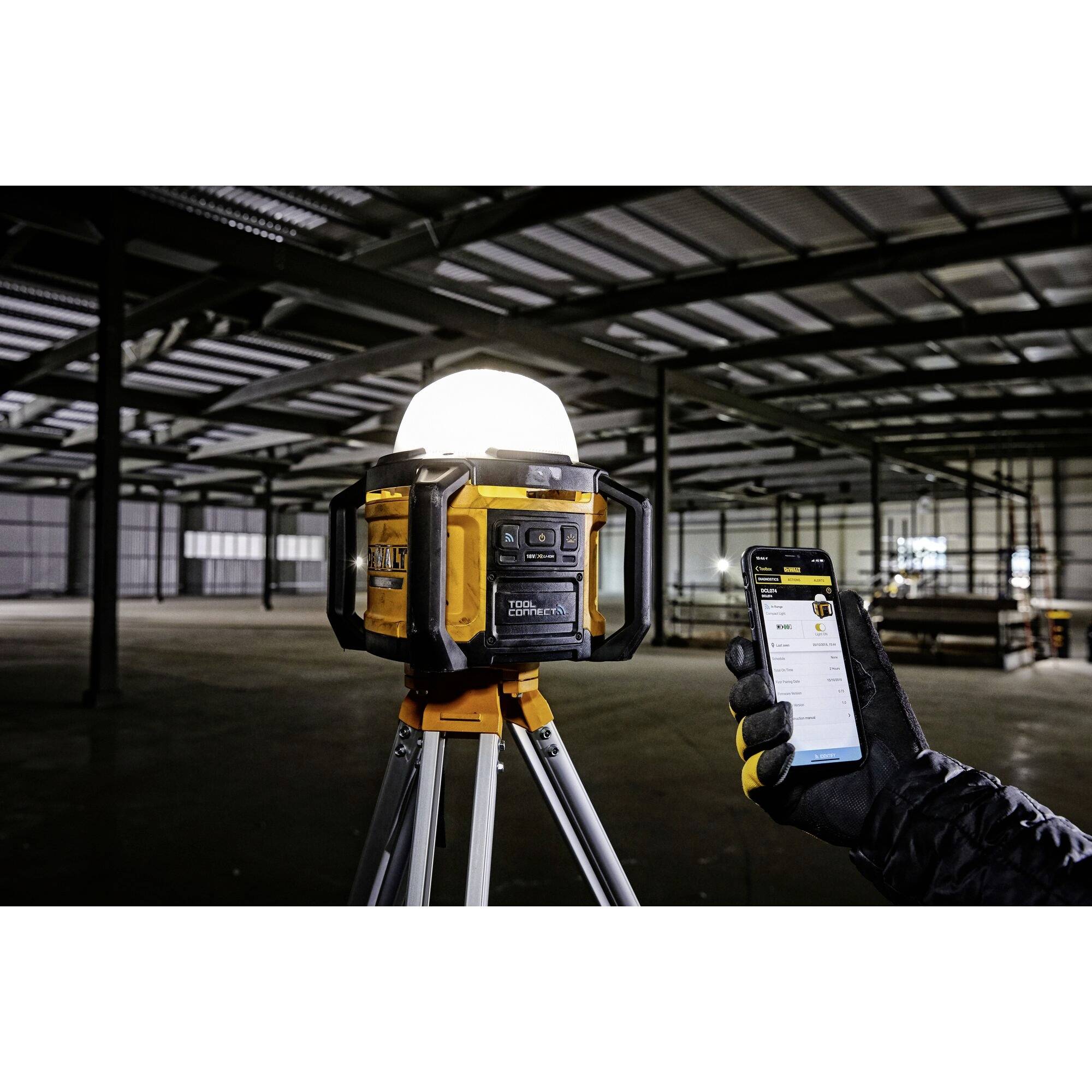 'Baustellenlaser in großer Halle, Person hält Smartphone mit App zur Steuerung des Lasers, zeigt technische Daten des Geräts.'