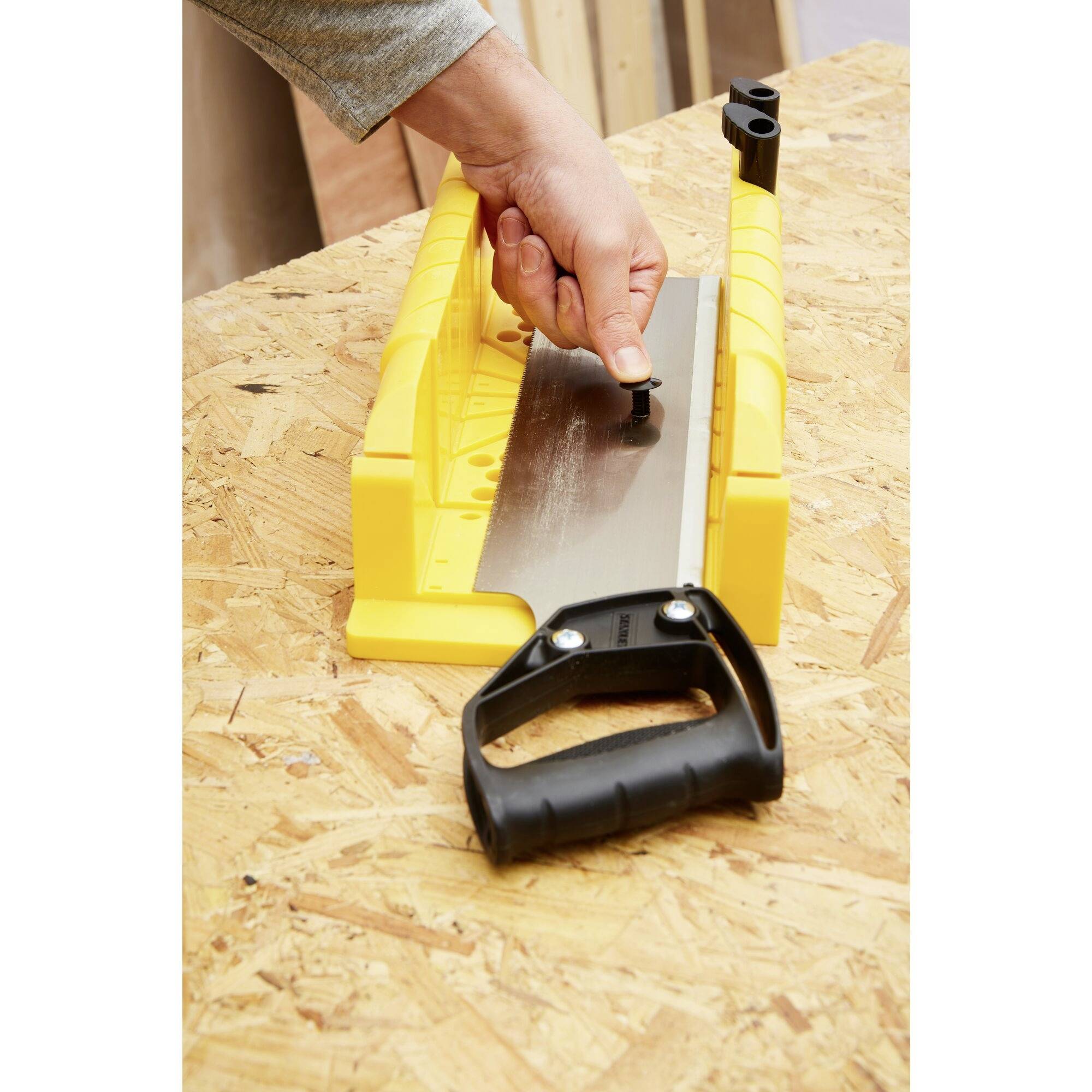 Eine Hand justiert das Blatt einer gelben Schärfhilfe auf einer Holzwerkbank.