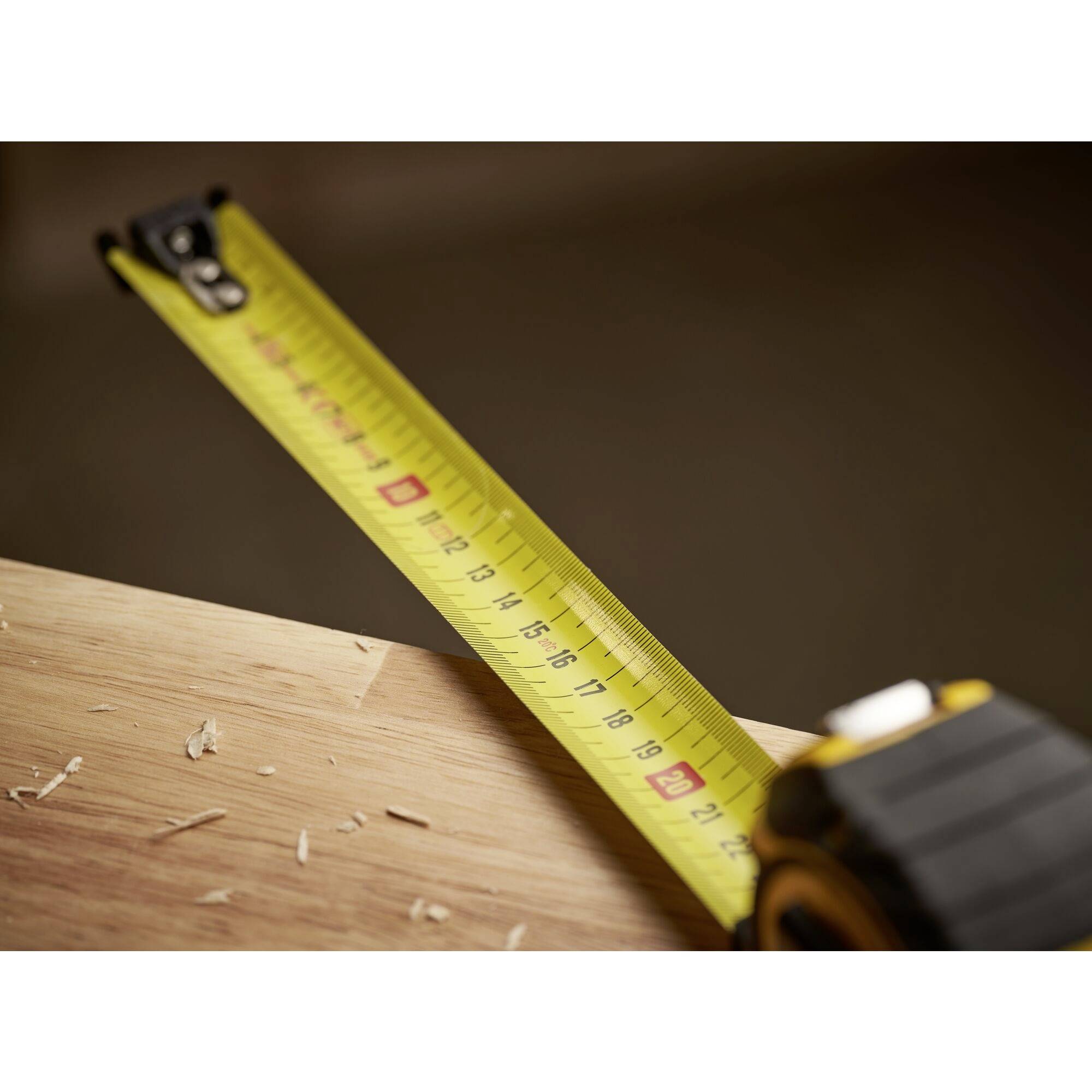 Ein Maßband liegt auf einem Holztisch, umgeben von Holzspänen, was auf handwerkliche Arbeiten hinweist.