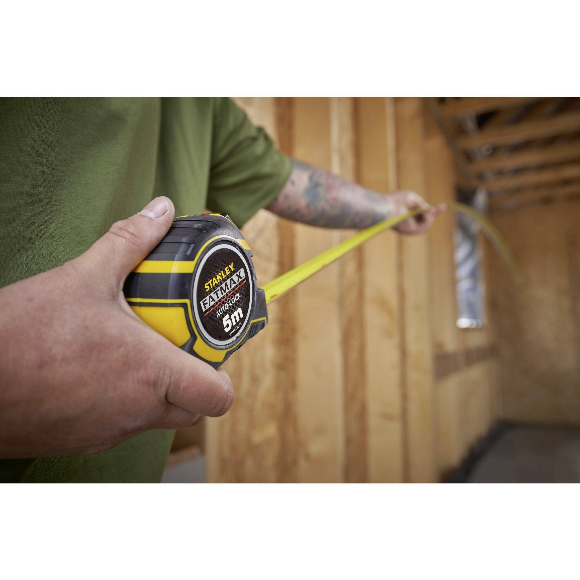 Eine Person hält ein ausgerolltes Maßband in einem im Bau befindlichen Raum, um eine Entfernung zu messen.