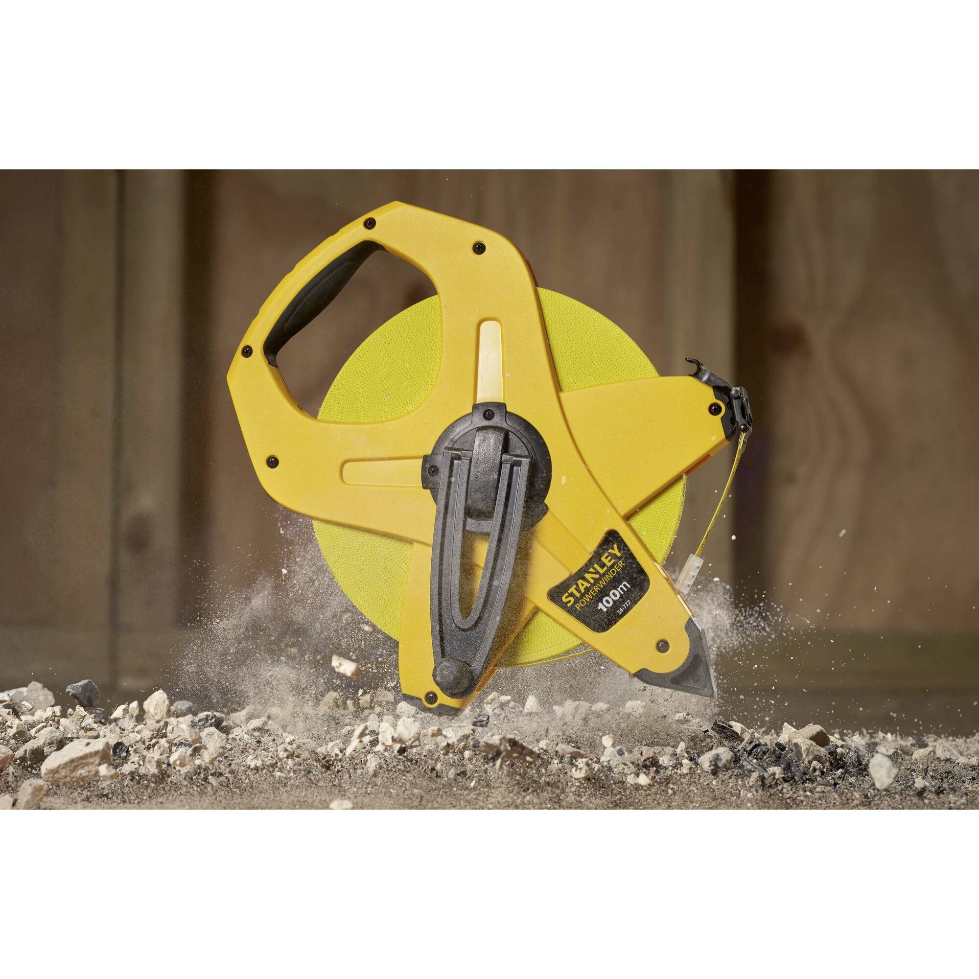 Ein gelbes Maßband liegt auf einer Baustelle, umgeben von Schutt und Staub, und symbolisiert Präzision und Bauvorbereitung.