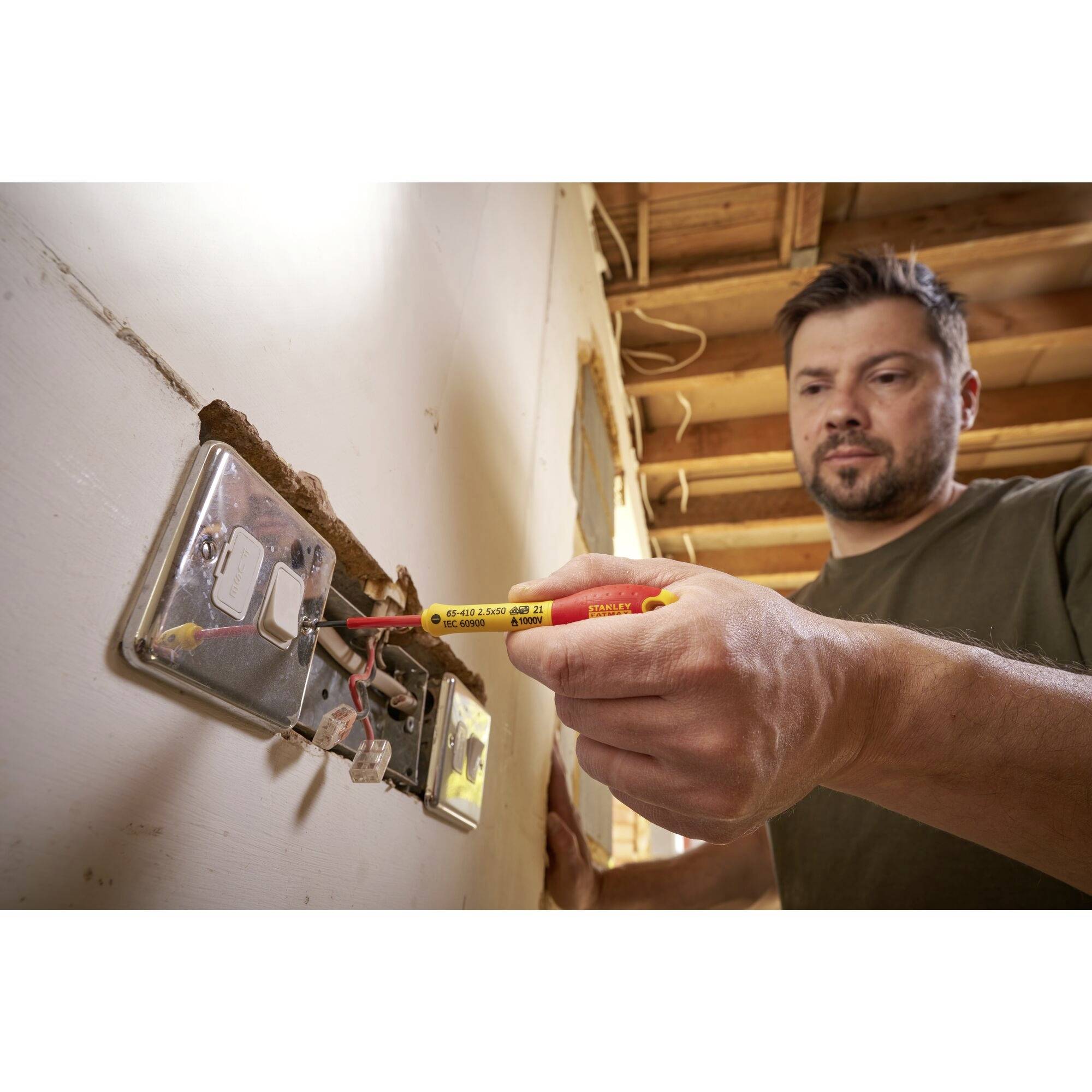 Eine Person repariert eine Steckdose mit einem Spannungsprüfer in einem teilweise renovierten Raum.