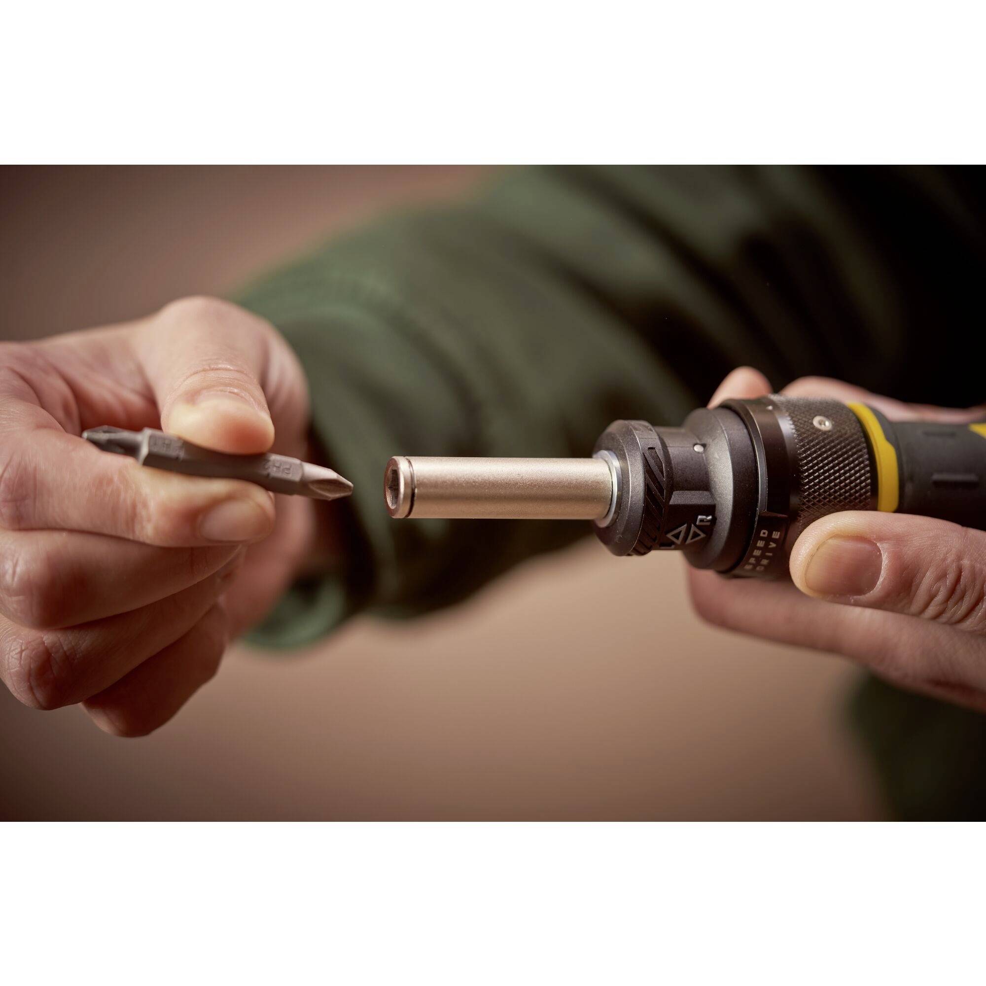 Eine Person hält einen Schraubendreher und eine Schraubendreherklinge und bereitet sich darauf vor, die Klinge in das Werkzeug einzusetzen.