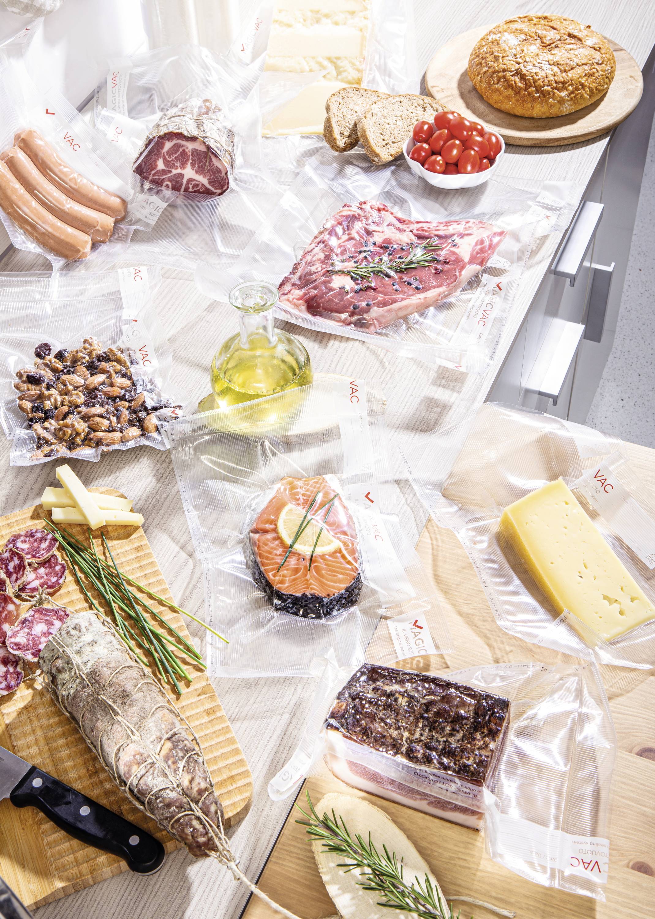 Verschiedene Lebensmittel, darunter Fleisch, Fisch, Käse und Gemüse, liegen vakuumverpackt auf einem Tisch, teils angeschnitten oder serviert.