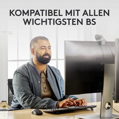 Ein Mann sitzt vor zwei Monitoren in einem Büro, darüber der Text 'KOMPATIBEL MIT ALLEN WICHTIGSTEN BS'.