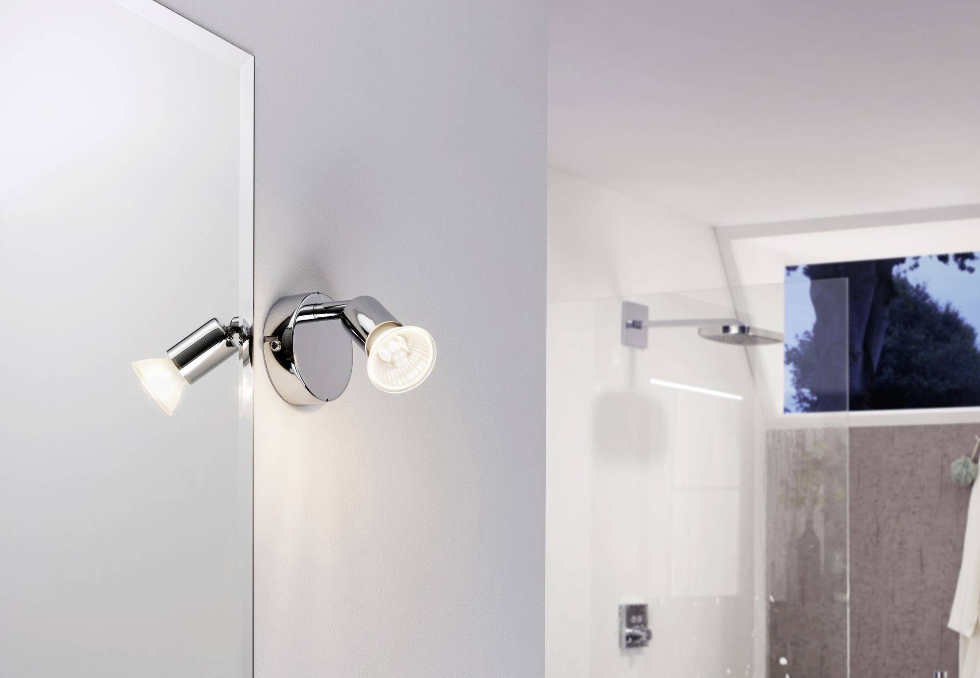 Zwei verstellbare Wandleuchten im Badezimmer, eine leuchtet zur Decke, die andere beleuchtet den Spiegel.