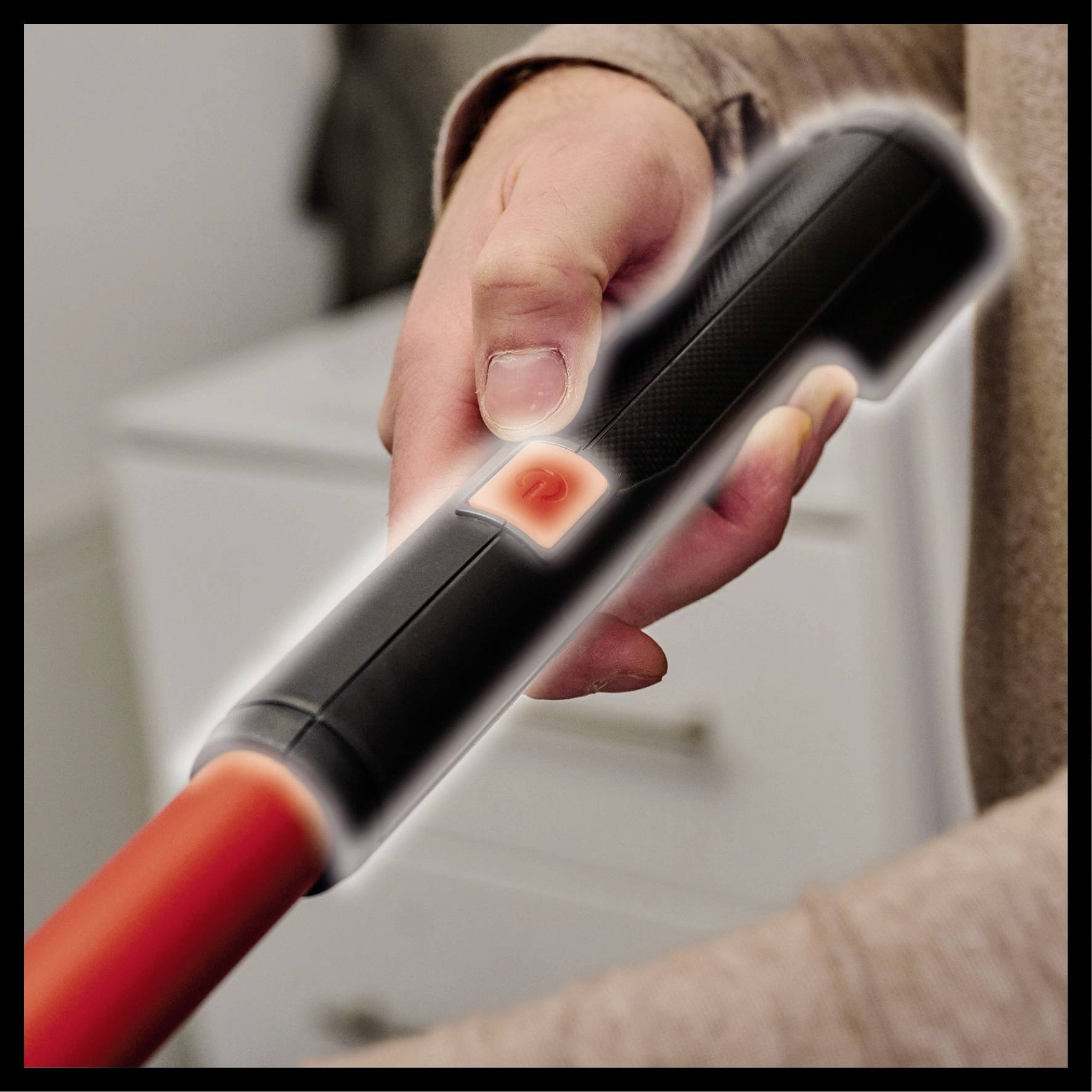 Eine Person hält eine Taschenlampe und drückt den Einschaltknopf, der rot leuchtet. Die Szene ist nah aufgenommen.