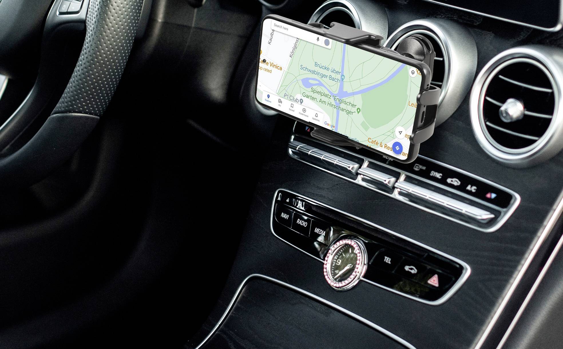 Smartphone-Navigation zeigt eine Karte in einem Auto, montiert am Armaturenbrett. Hauptstraßen und Fluss erkennbar.