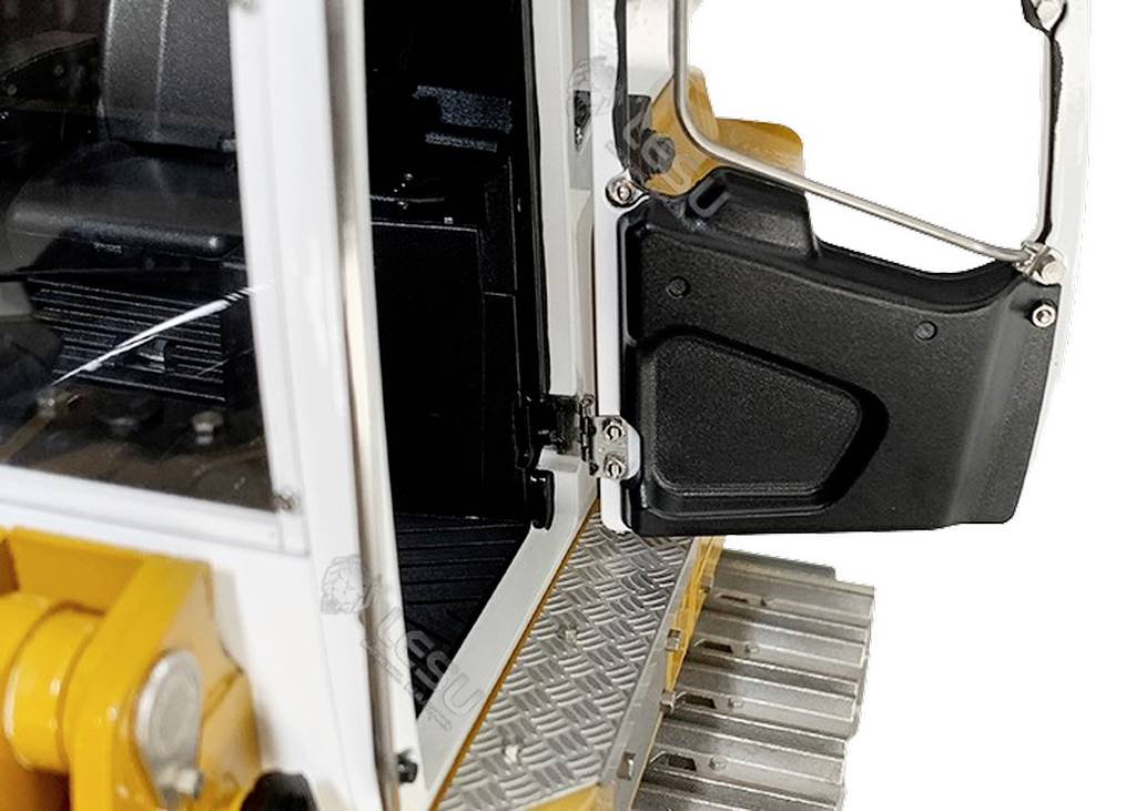 'Nahaufnahme einer offenen Tür eines gelben Bauwagens. Die Trittfläche ist aus Metall und geriffelt. Der Innenraum und das Scharnier sind sichtbar.'