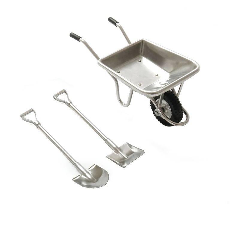 Schubkarre und zwei Schaufeln aus Metall auf weißem Hintergrund, alle mit ergonomischen Griffen. Geeignet für Garten- oder Bauarbeiten.