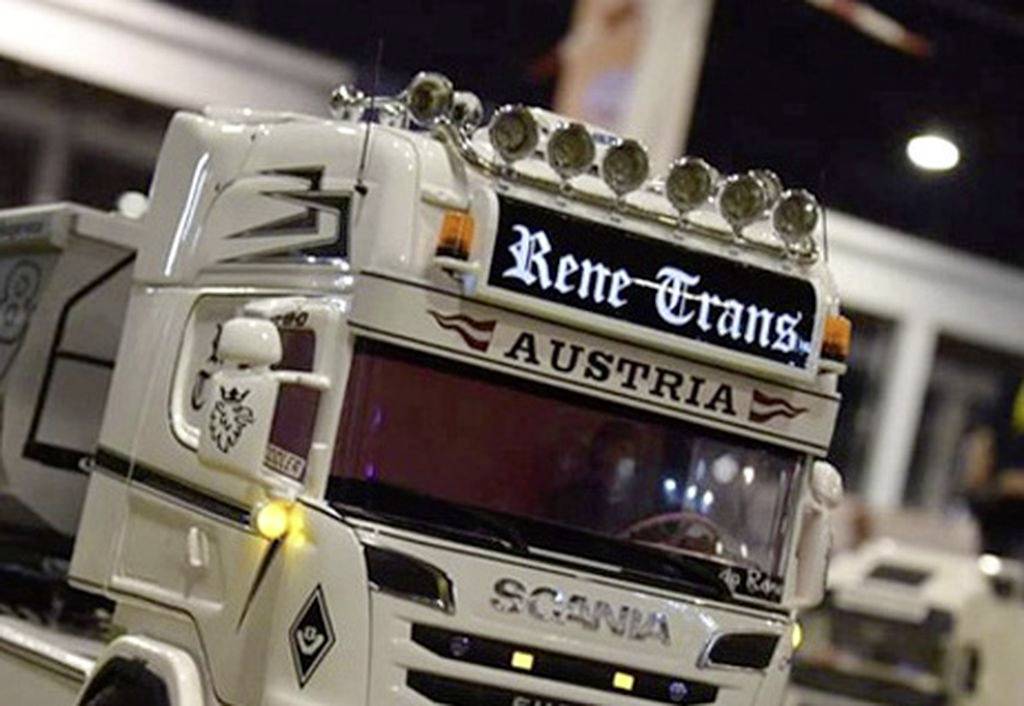 Spielzeug-Lastwagen im Miniaturformat mit der Aufschrift 'Rene Trans AUSTRIA' auf der Frontscheibe, umgeben von anderen Miniaturen.