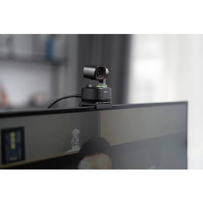 Eine Webcam ist auf einem Monitor montiert. Im Hintergrund ist ein unscharfes Bücherregal zu sehen.