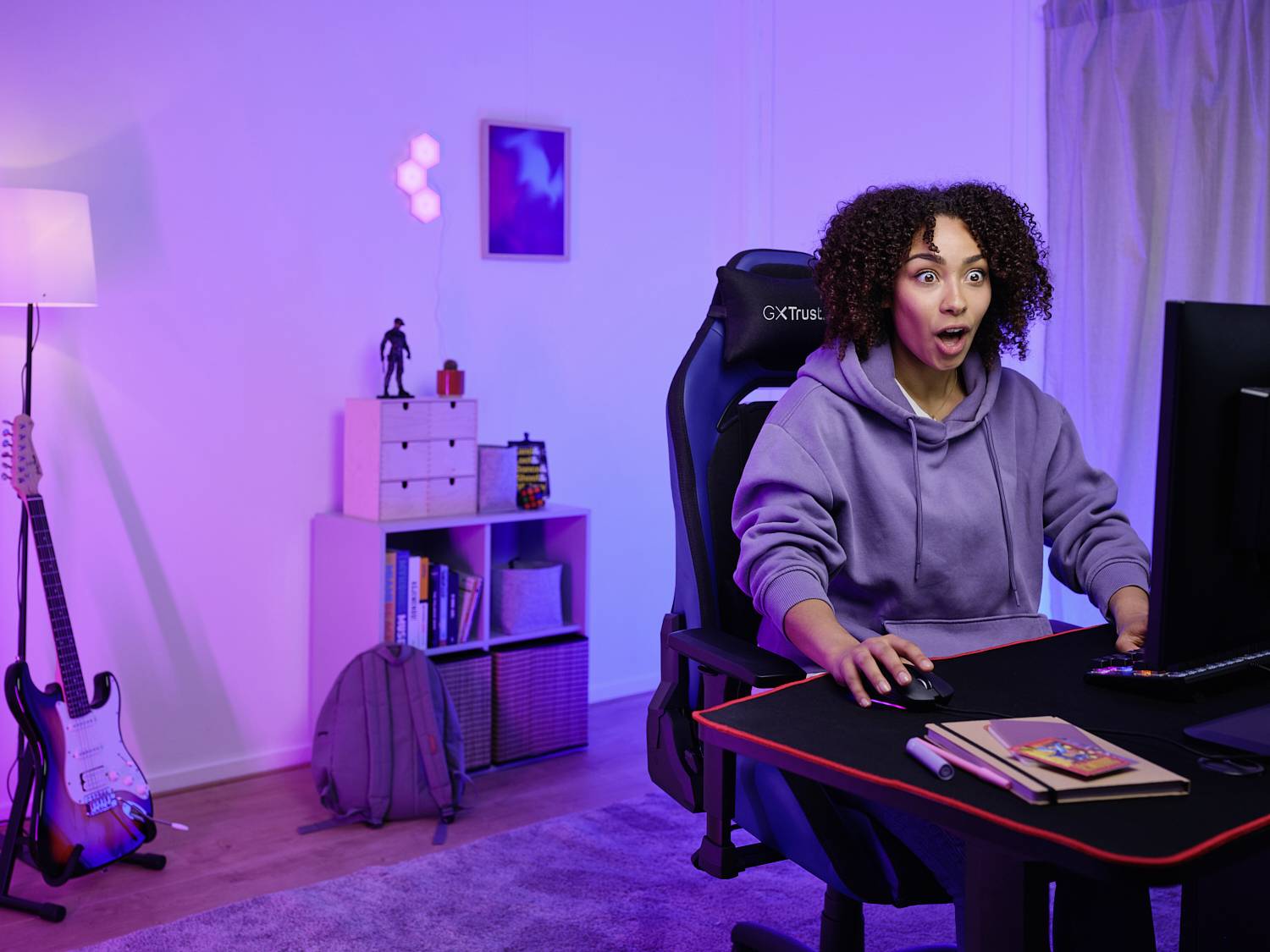 Eine Person sitzt an einem Schreibtisch mit einem Computer und hat einen überraschten Gesichtsausdruck. Der Raum ist modern eingerichtet mit sanfter Beleuchtung.