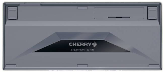 Die Rückseite einer grauen Tastatur, Modell 'CHERRY KW 7100 MINI'. Oben links sind zwei verstellbare Stützen zu sehen.