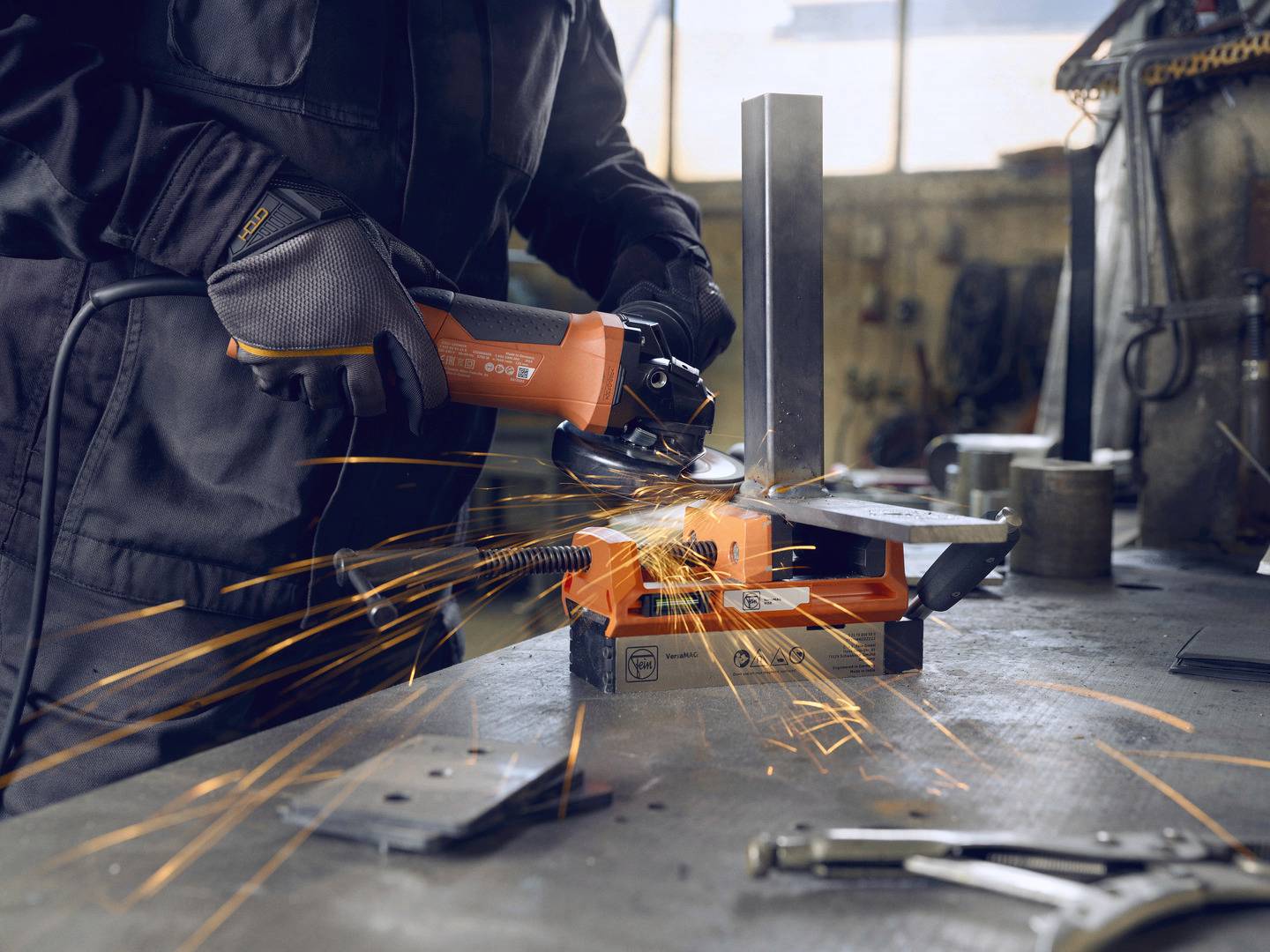 Eine Person schneidet Metall mit einem Winkelschleifer, funkelnde Funken fliegen auf einer Werkbank in einer Werkstatt.