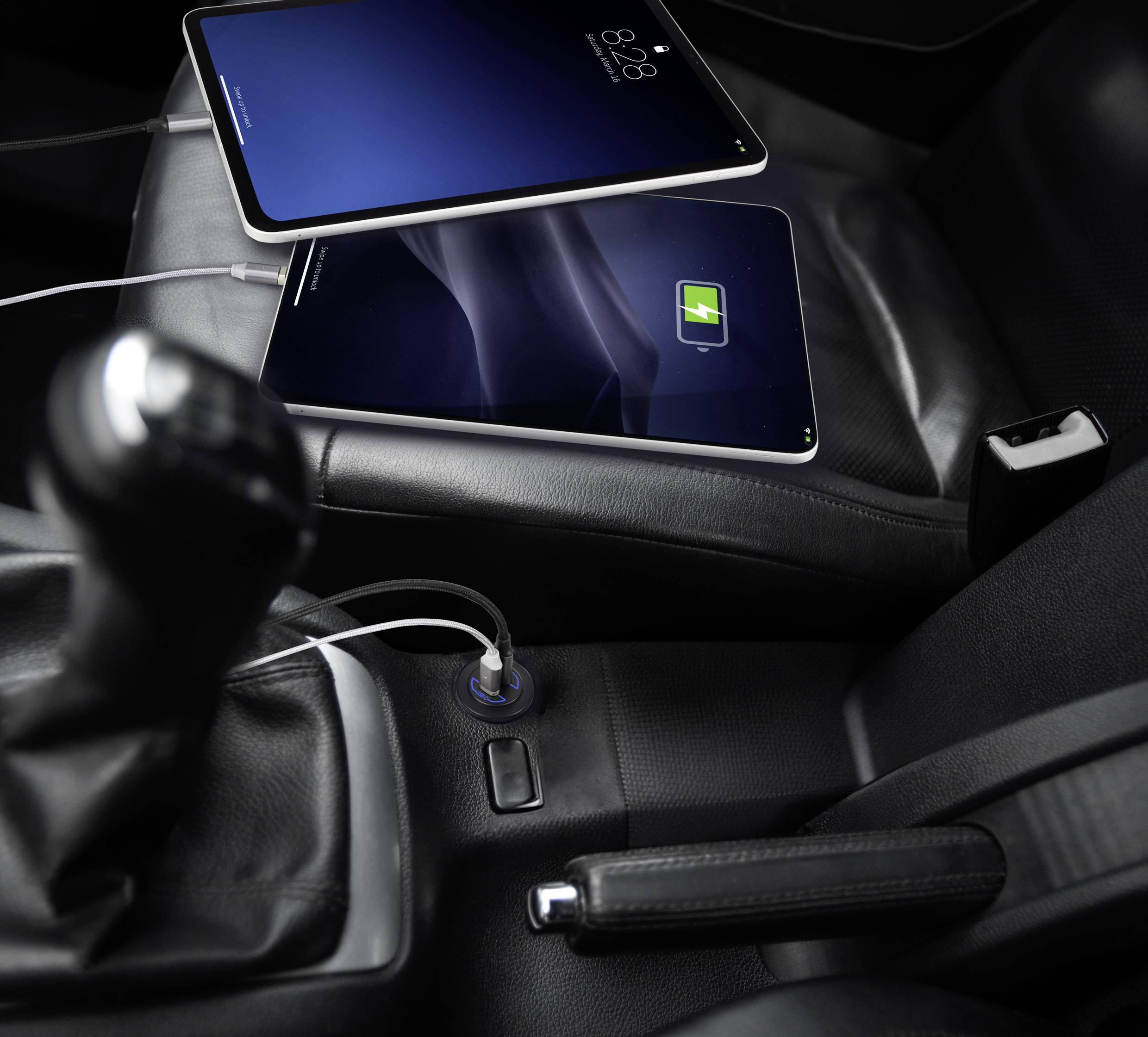 Zwei Tablets am Laden im Auto. Ein Tablet zeigt einen grünen Ladezustand, das andere hat dunklen Bildschirm. Beide sind an den Zigarettenanzünder angeschlossen.