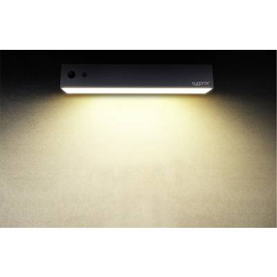 Eine rechteckige Wandlampe strahlt sanftes, warmweißes Licht auf eine beige Wand. Markenname in der oberen rechten Ecke.