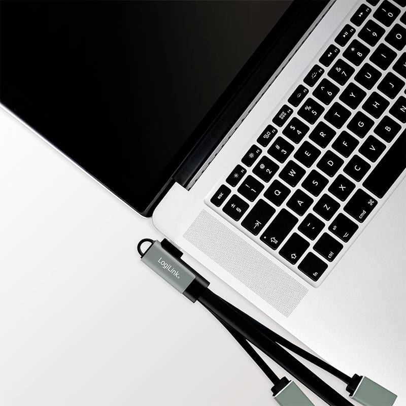 Laptop auf einem Tisch mit zwei USB-Kabeln, die daneben liegen. Oben rechts ist die Tastatur sichtbar.