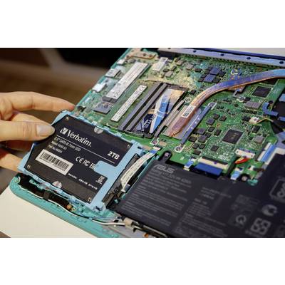 Eine Hand installiert eine SSD-Festplatte in einen Laptop, dessen Gehäuse offen ist und die interne Elektronik sichtbar macht.