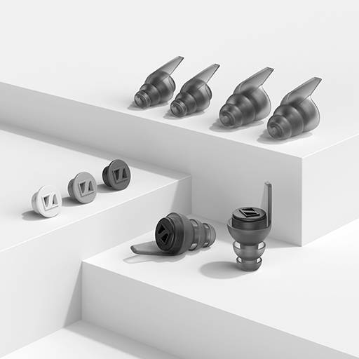 Mehrere schwarze und graue Ohrstöpsel in verschiedenen Designs auf einem weißen, stufenförmigen Hintergrund angeordnet.