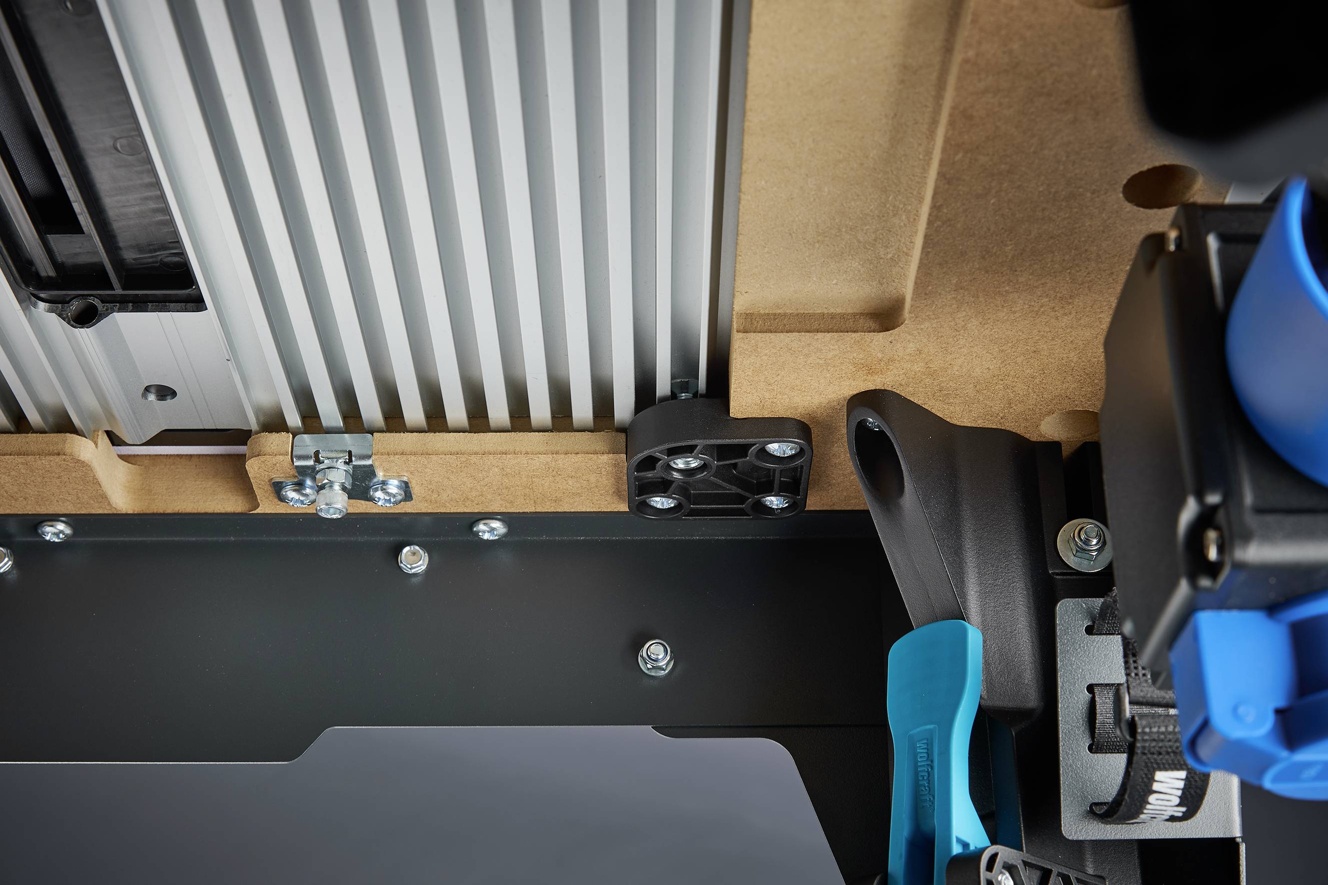 Ein Makrofoto eines Maschinenbauteils mit Metallschrauben, einem blauen Hebel und strukturierten Oberflächen.