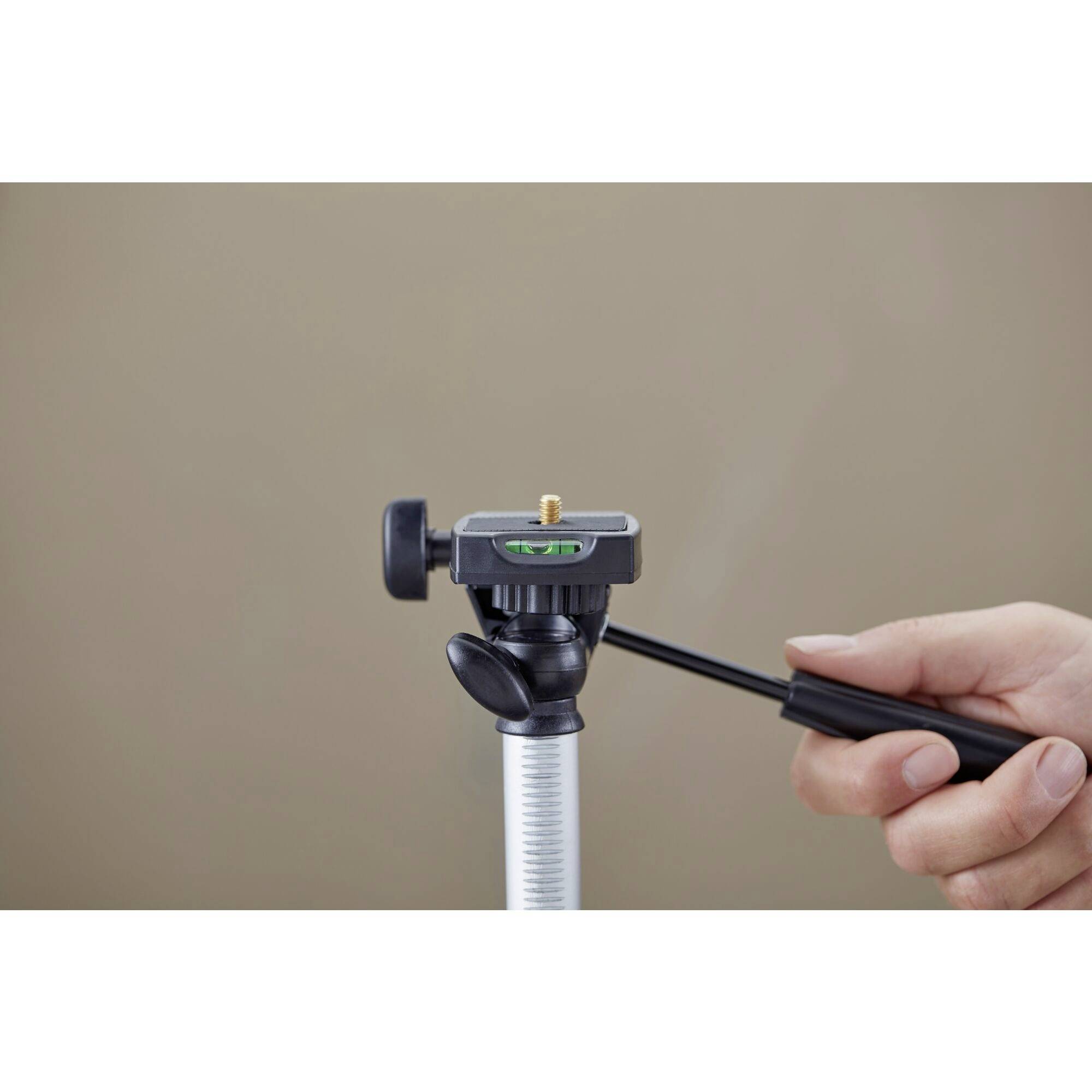 Ein Kamera-Stativkopf mit Wasserwaage, gehalten von einer Hand, bereit zur Justierung auf einem braunen Hintergrund.