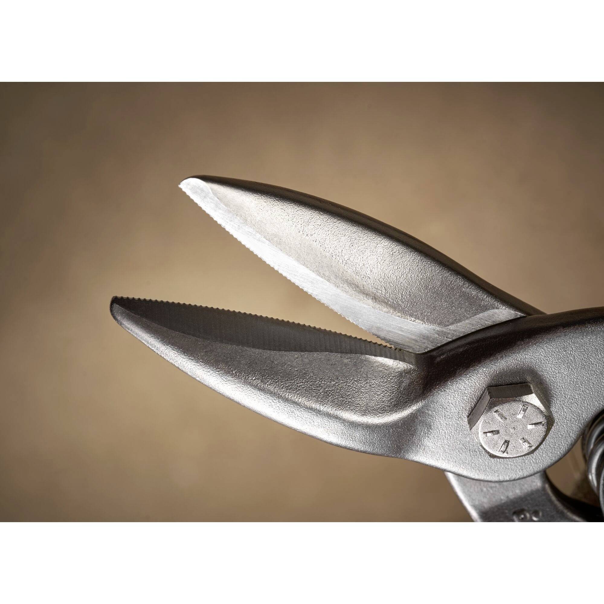 Eine offene Metallschere mit gezackten Klingen, die eine Nahaufnahme zeigt.