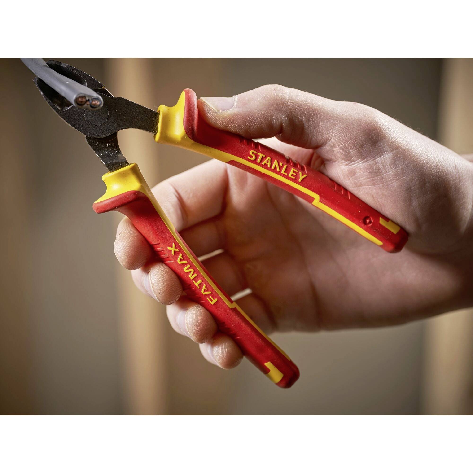 Eine Hand hält eine rote Kombizange mit gelben Akzenten, auf der 'Stanley' und 'Fatmax' steht. Die Zange ist teilweise geöffnet.