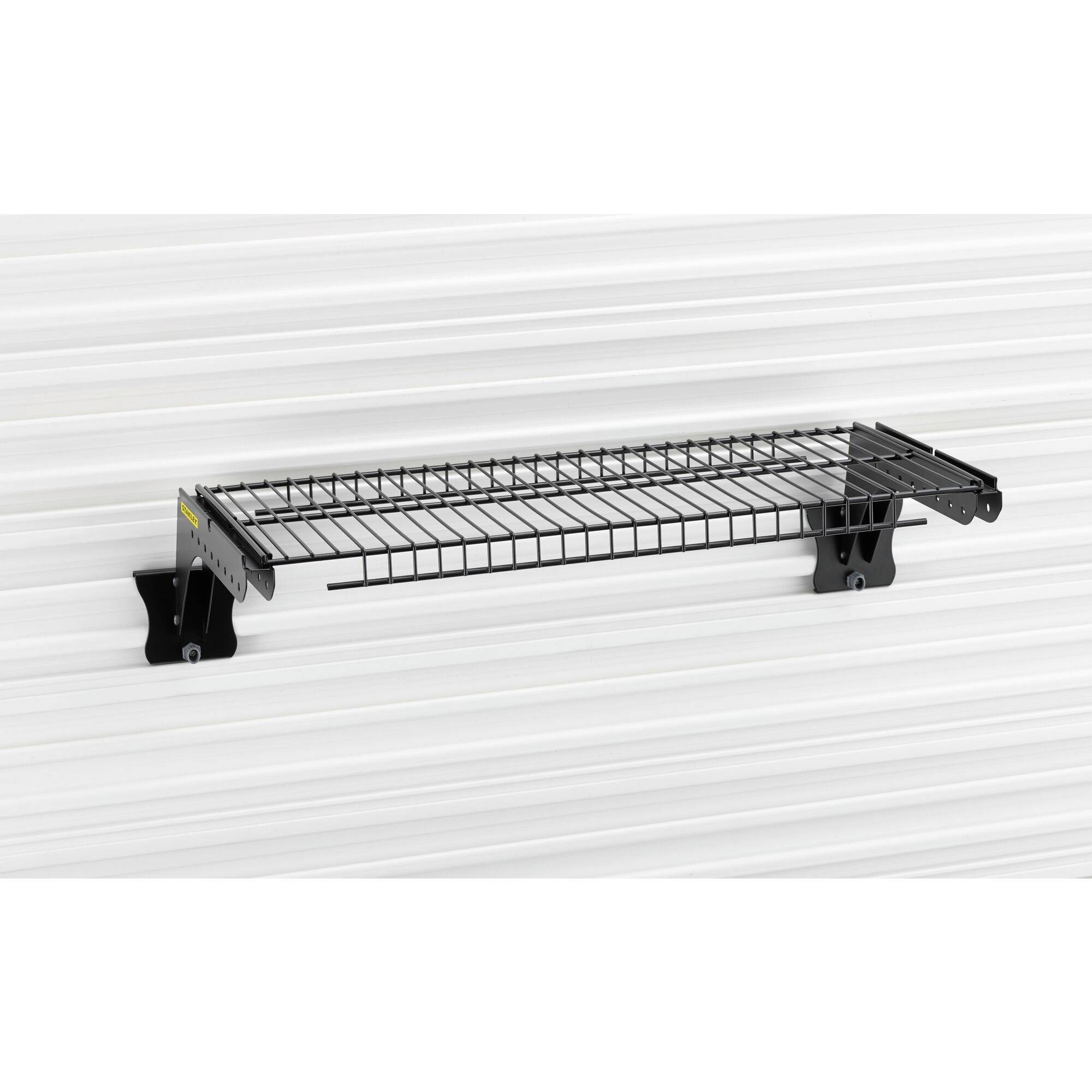 Ein schwarzes Wandregal aus Metallgitter, montiert auf einer gestreiften weißen Wand. 