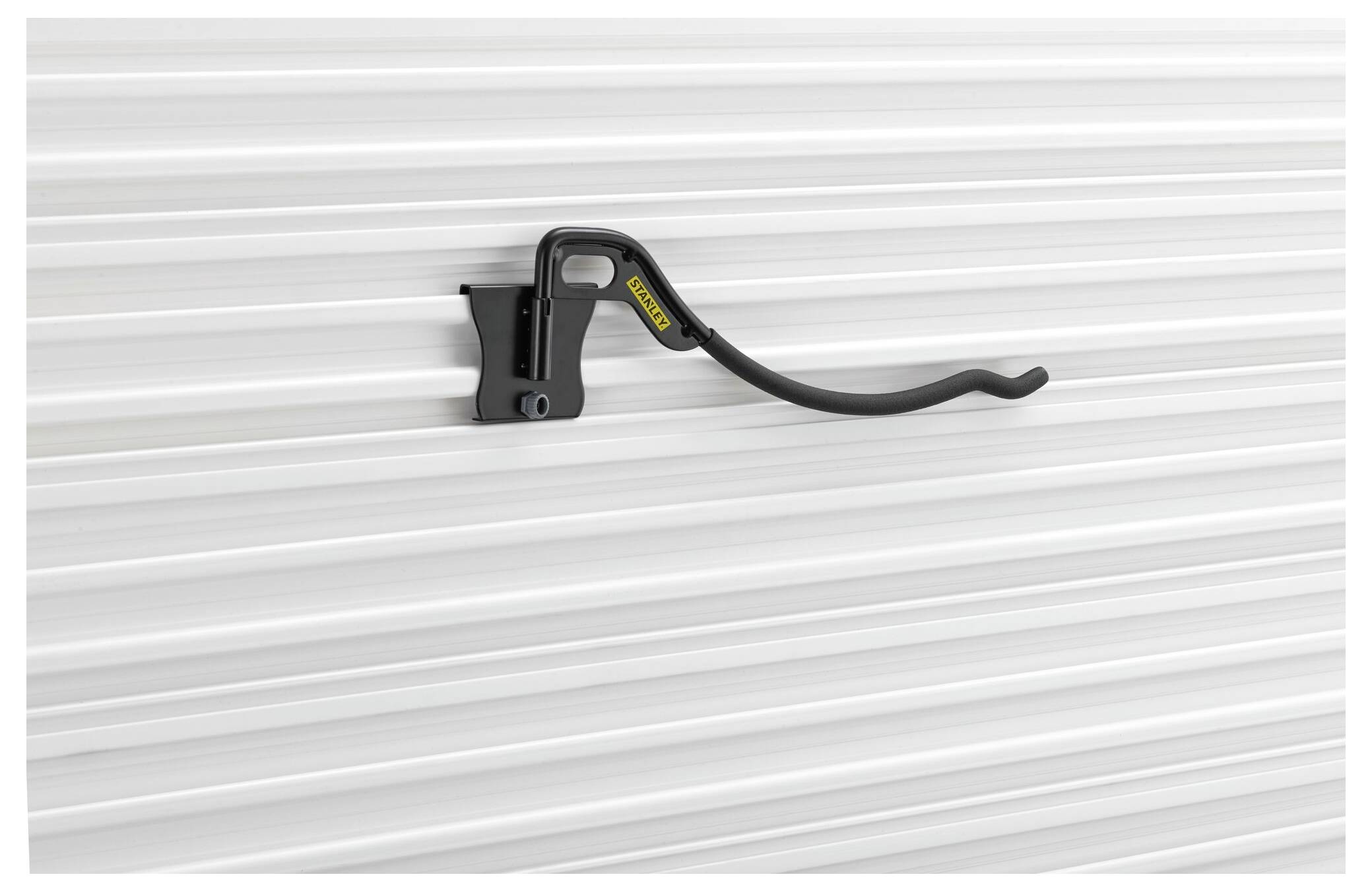 Fahrradhaken, der an einer weißen Wand montiert ist, zeigt eine horizontale Wellenstruktur. Der Haken hat ein schwarzes, gebogenes Design.