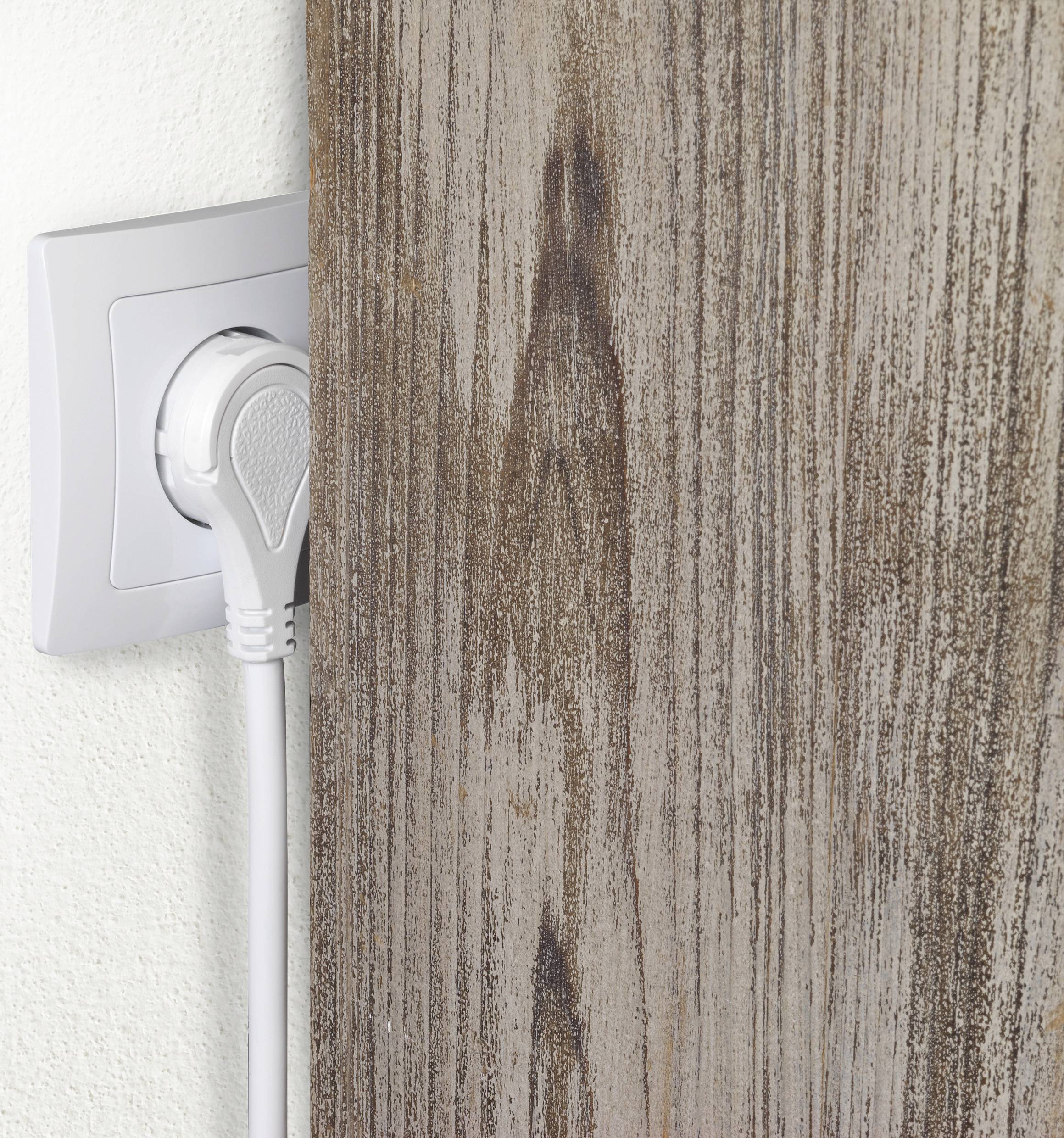 Ein Stecker ist in eine Wandsteckdose eingesteckt, wobei ein Holzbrett fast den Stecker vollständig verdeckt.