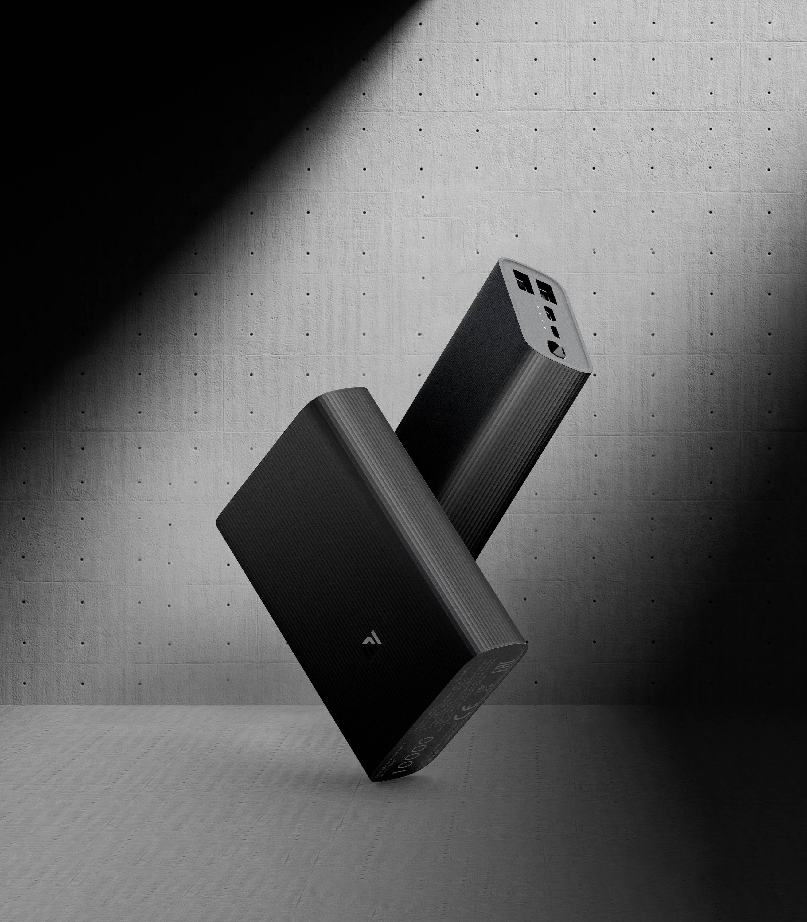 Zwei schwarze Lautsprecher in modernem Design stehen schräg auf einer Betonfläche, beleuchtet von einem einzelnen Spotlicht.