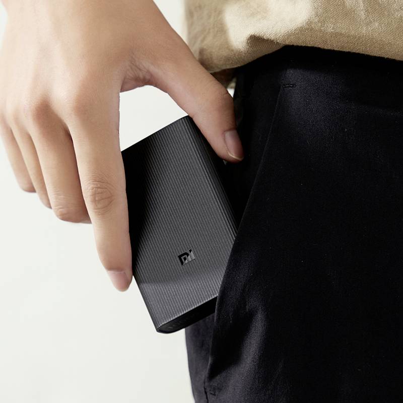 Eine Person steckt eine schwarze Powerbank in die Tasche.