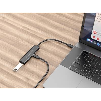 Ein Laptop ist über einen USB-C-Hub mit einem USB-Stick verbunden, der auf einem Holztisch liegt.