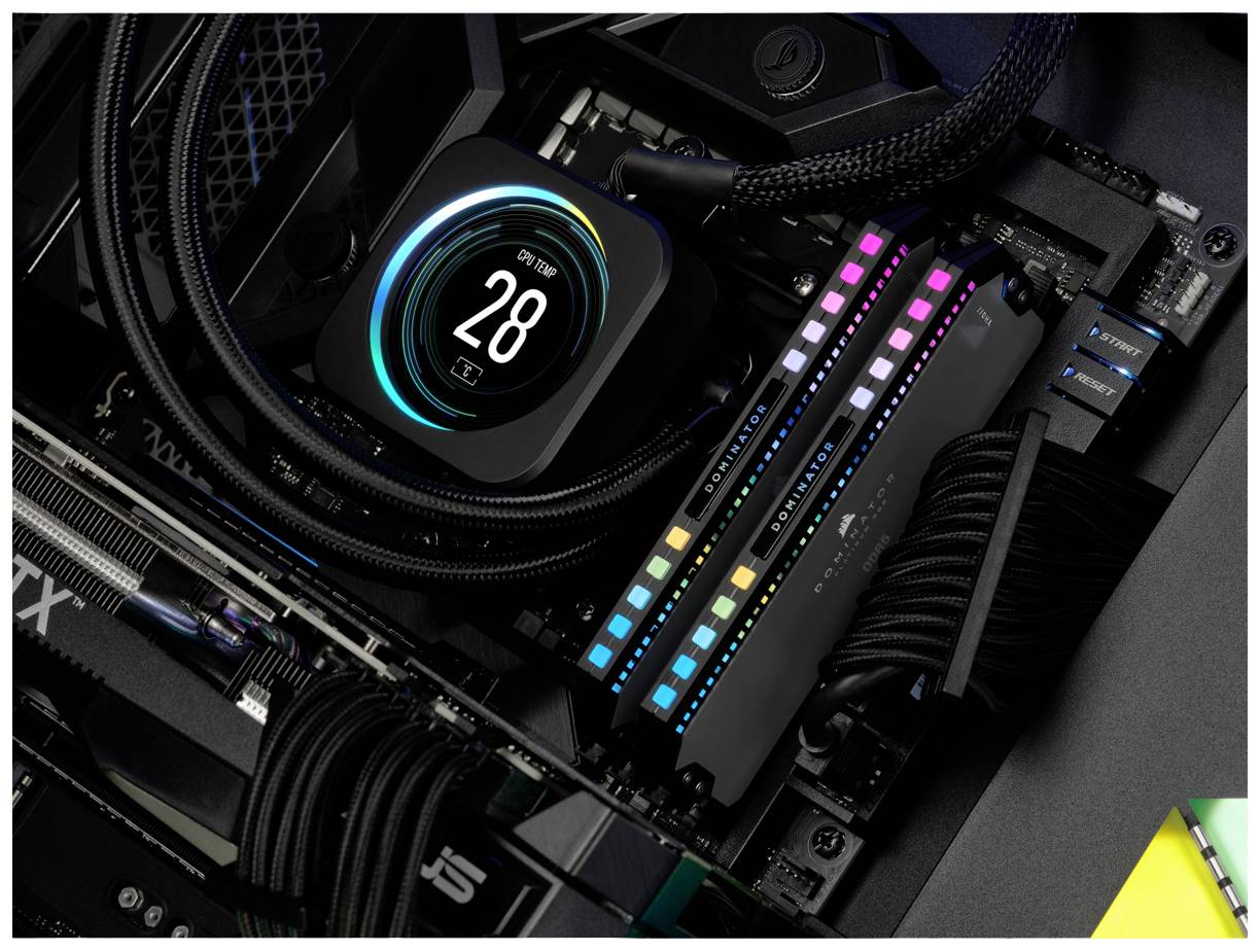 Ein offener Computer zeigt eine CPU-Kühleranzeige mit Temperatur '28°C' und bunte RGB-RAM-Sticks.
