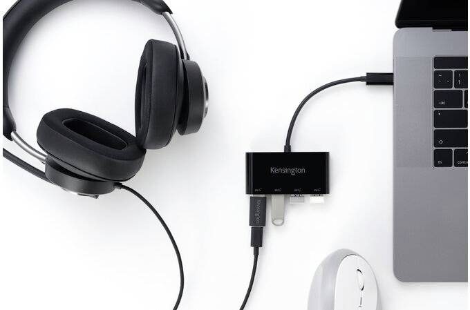 'Ein schwarzes Headset, ein USB-Hub und eine Maus sind an einen Laptop angeschlossen.'